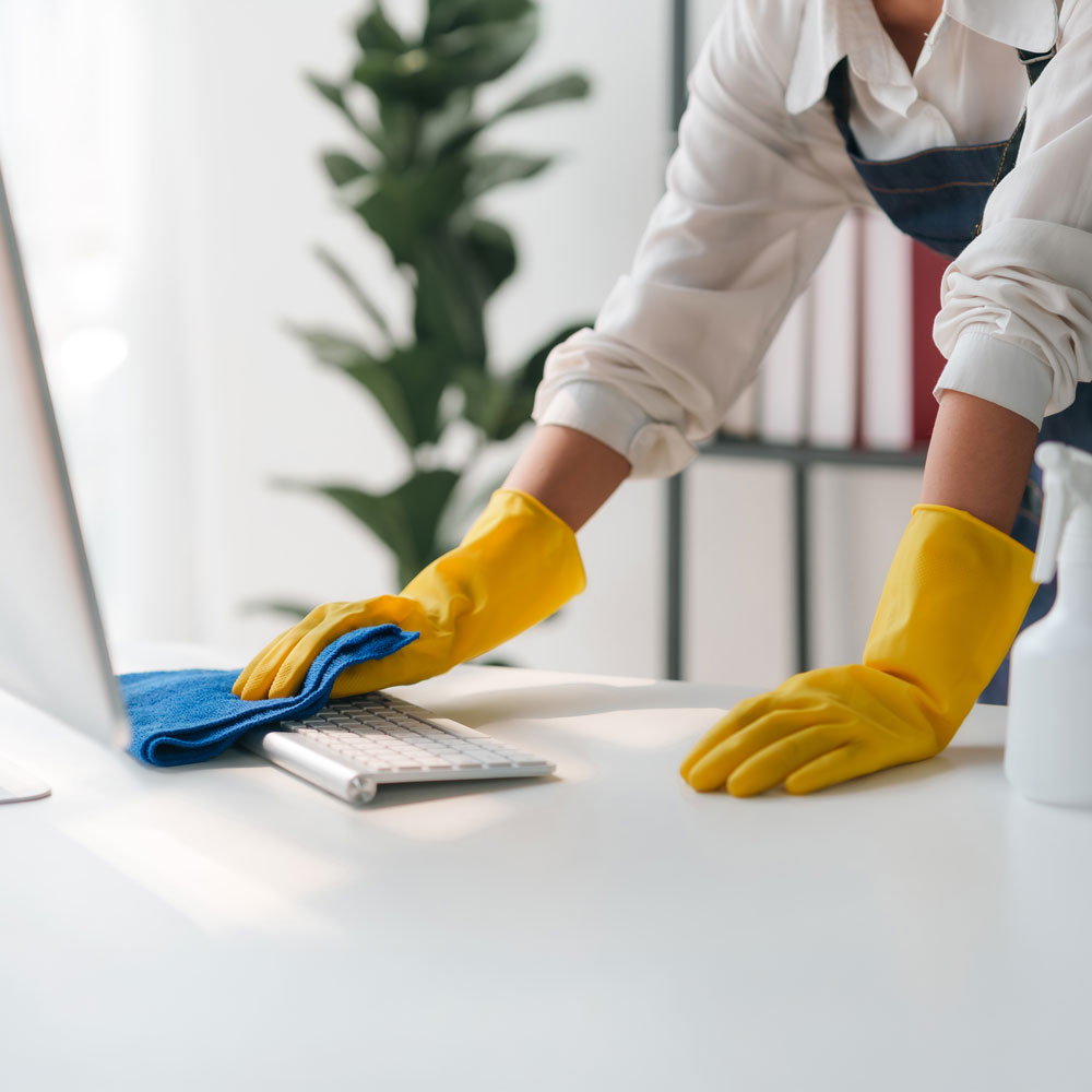 Büroreinigung - Frau putzt Tastatur.